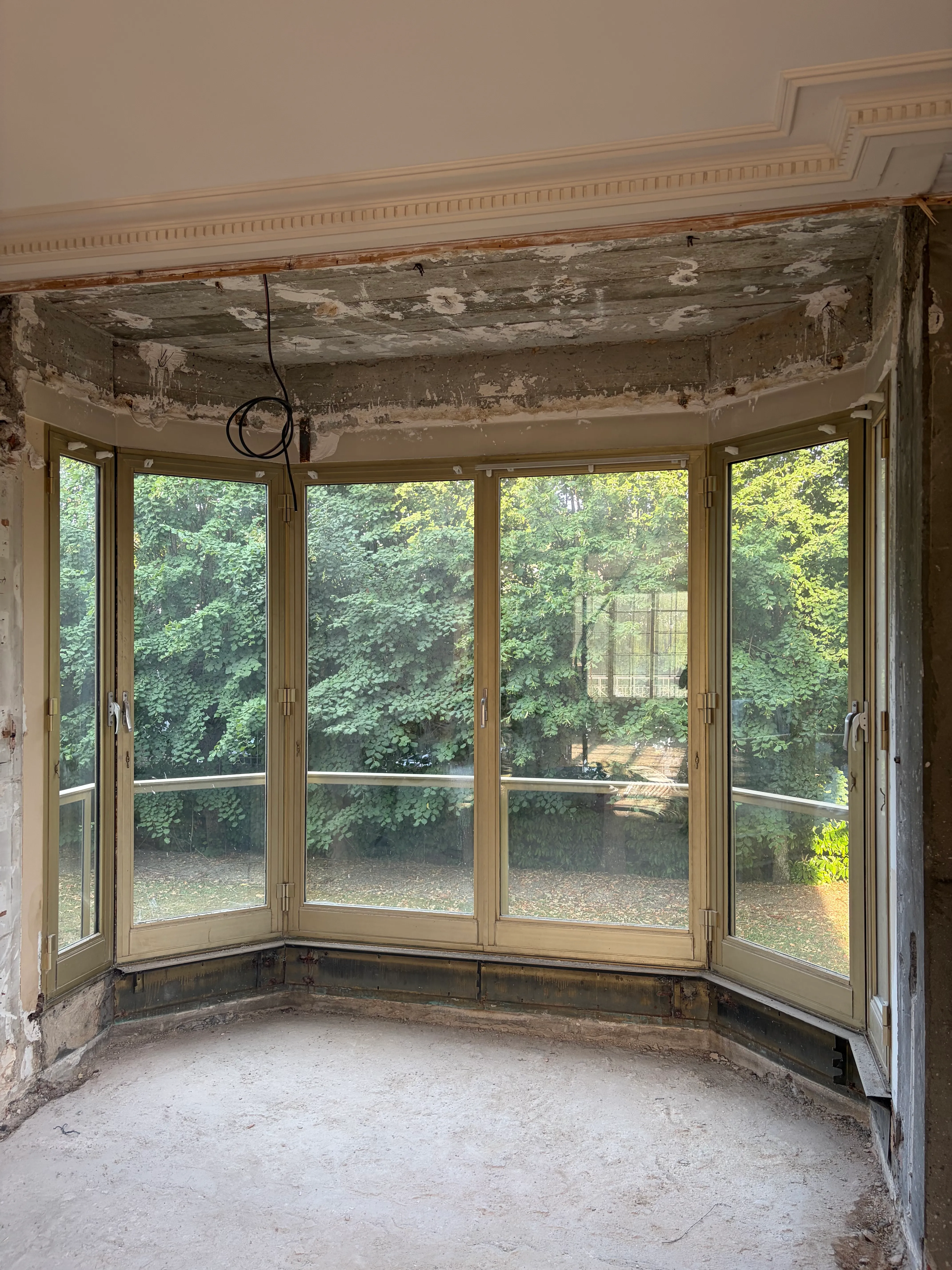 Vue latérale d'un ancien bow window en bois avec son radiateur