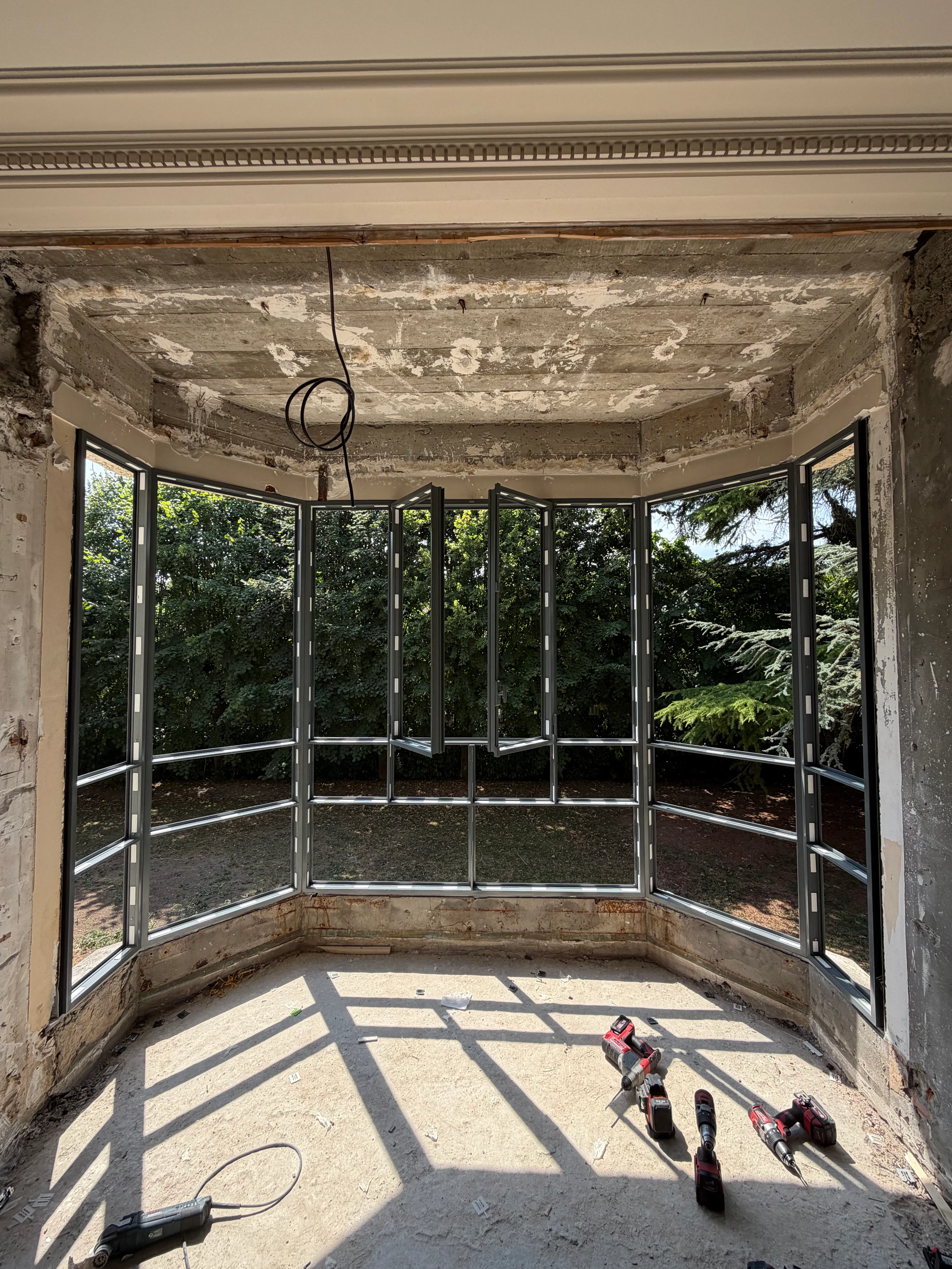 Assemblage et pose de la nouvelle structure de bow window en aluminium avec outils sur le sol