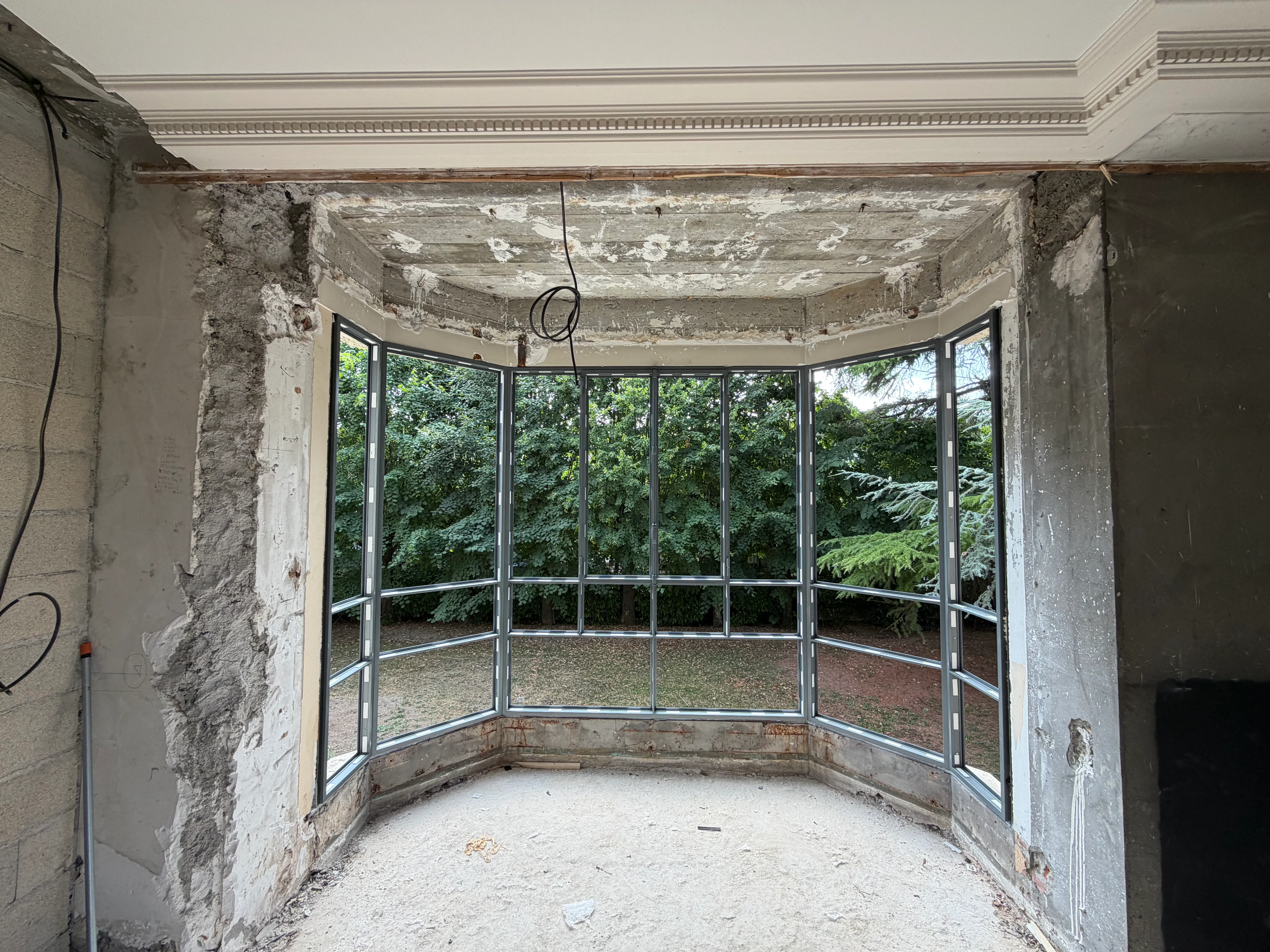 Nouvelle structure de bow window en aluminium installée, vue depuis l'intérieur de la pièce en travaux