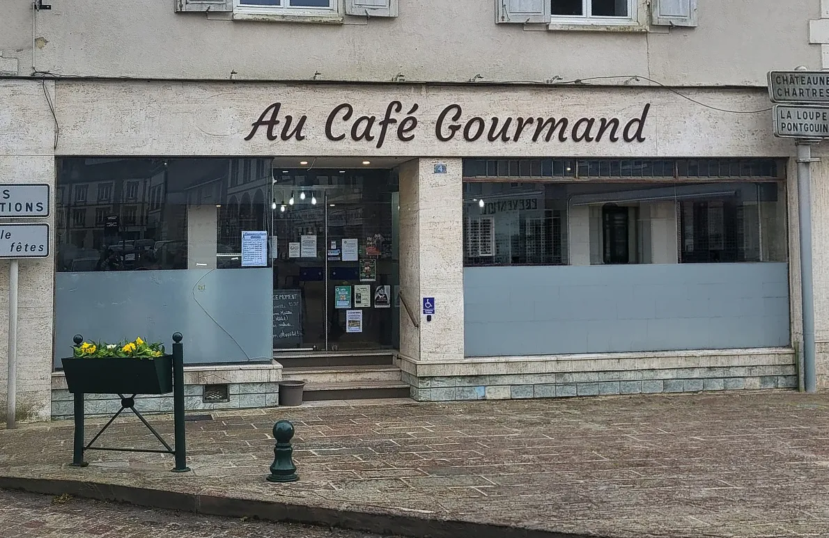 État initial de l'ancienne devanture du restaurant avant rénovation, montrant des panneaux inférieurs gris et des menuiseries usées à remplacer.