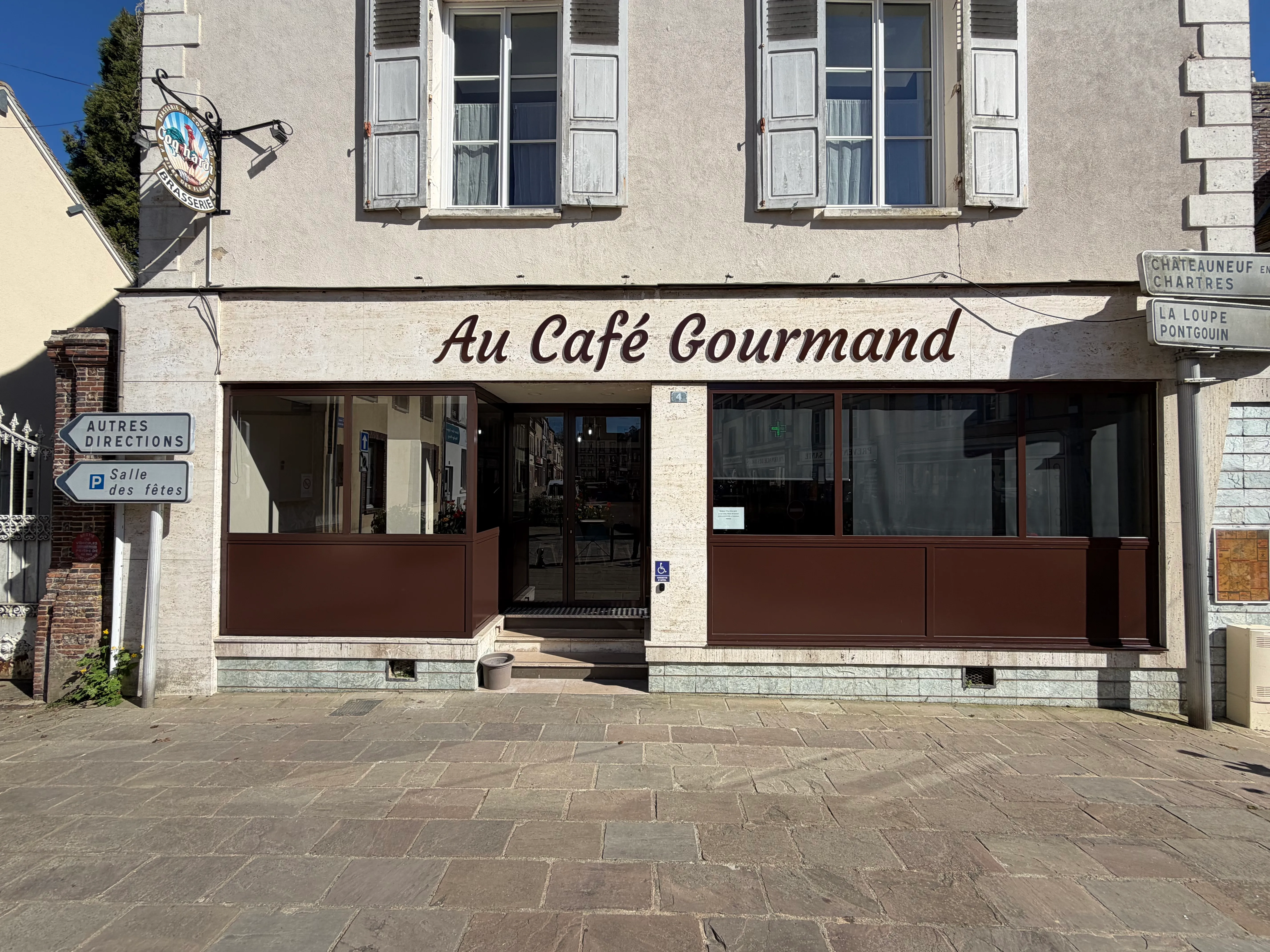 Remplacement de vitrine commerciale en acier et aluminium - Serrurerie fine Eure-et-Loir Façade extérieure rénovée d'un commerce affichant une vitrine moderne avec ossature en acier et panneaux inférieurs en tôle d'aluminium assortis au logo.