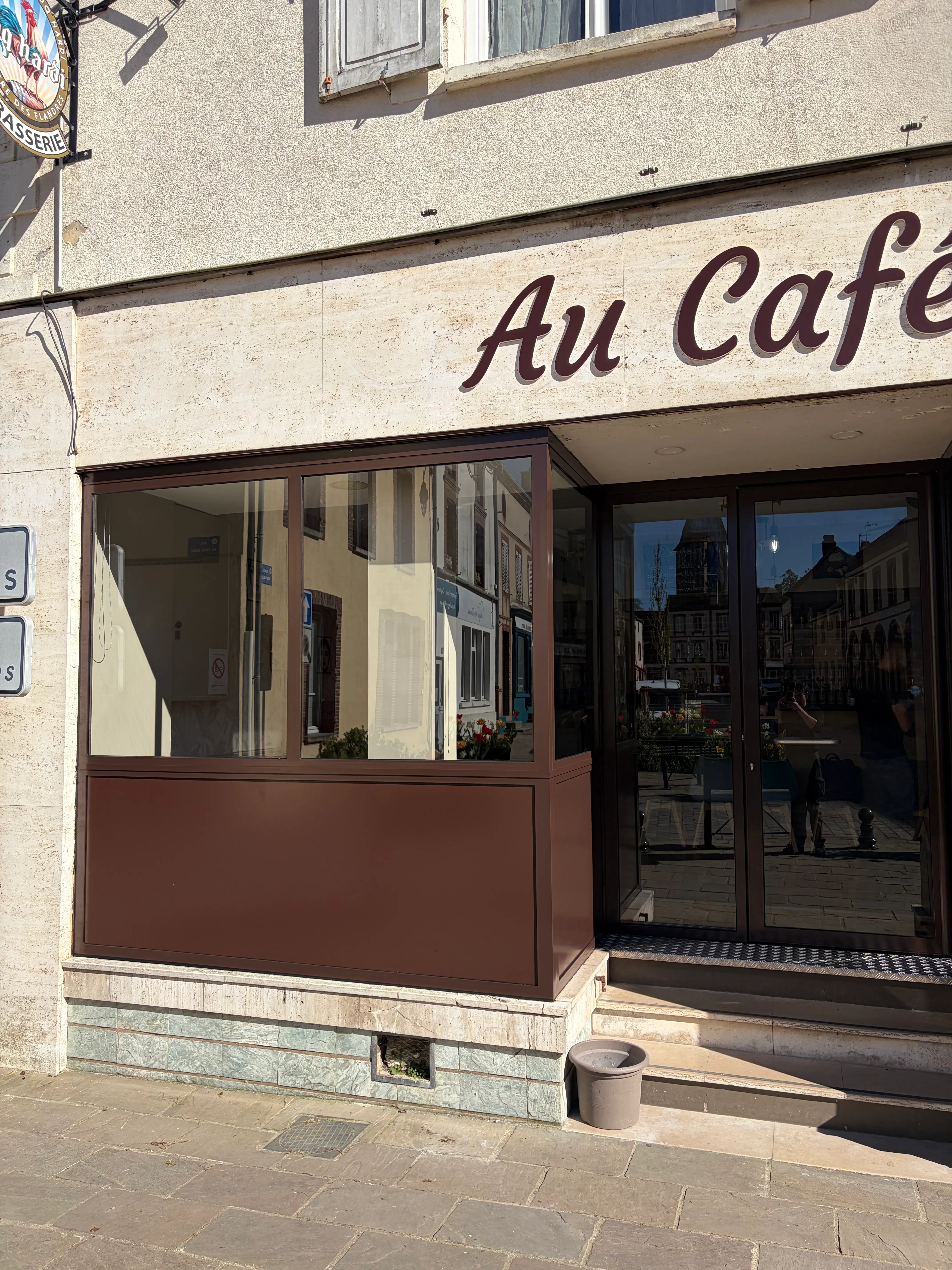 Vue en perspective de la nouvelle porte d'entrée et de la vitrine métallique du restaurant, soulignant l'intégration parfaite de la structure acier dans la façade.