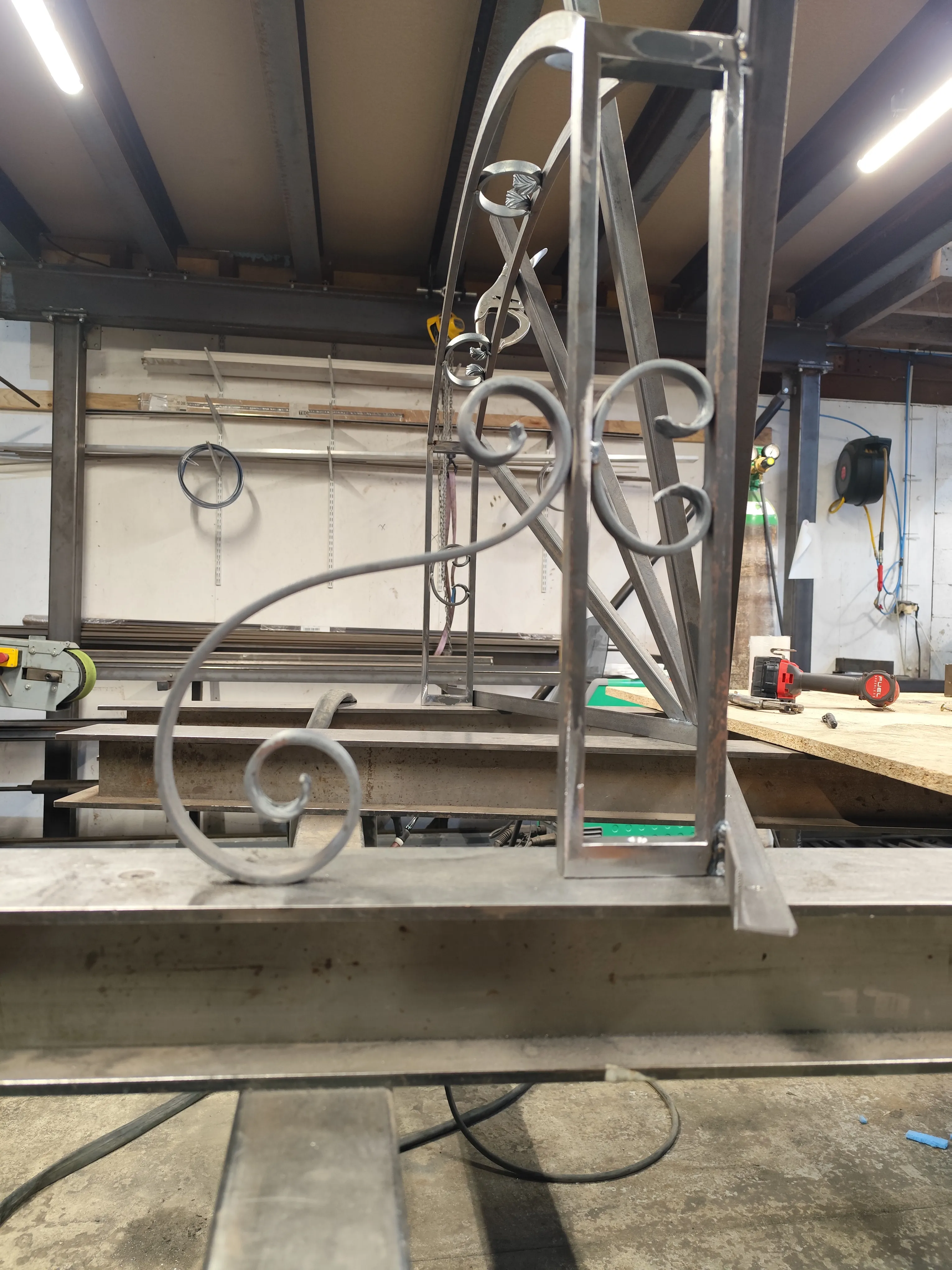 Détail des motifs à volutes en acier pour marquise sur mesure Détail en gros plan d'une volute en acier soudée sur la structure d'une marquise en cours de fabrication dans un atelier de métallerie.