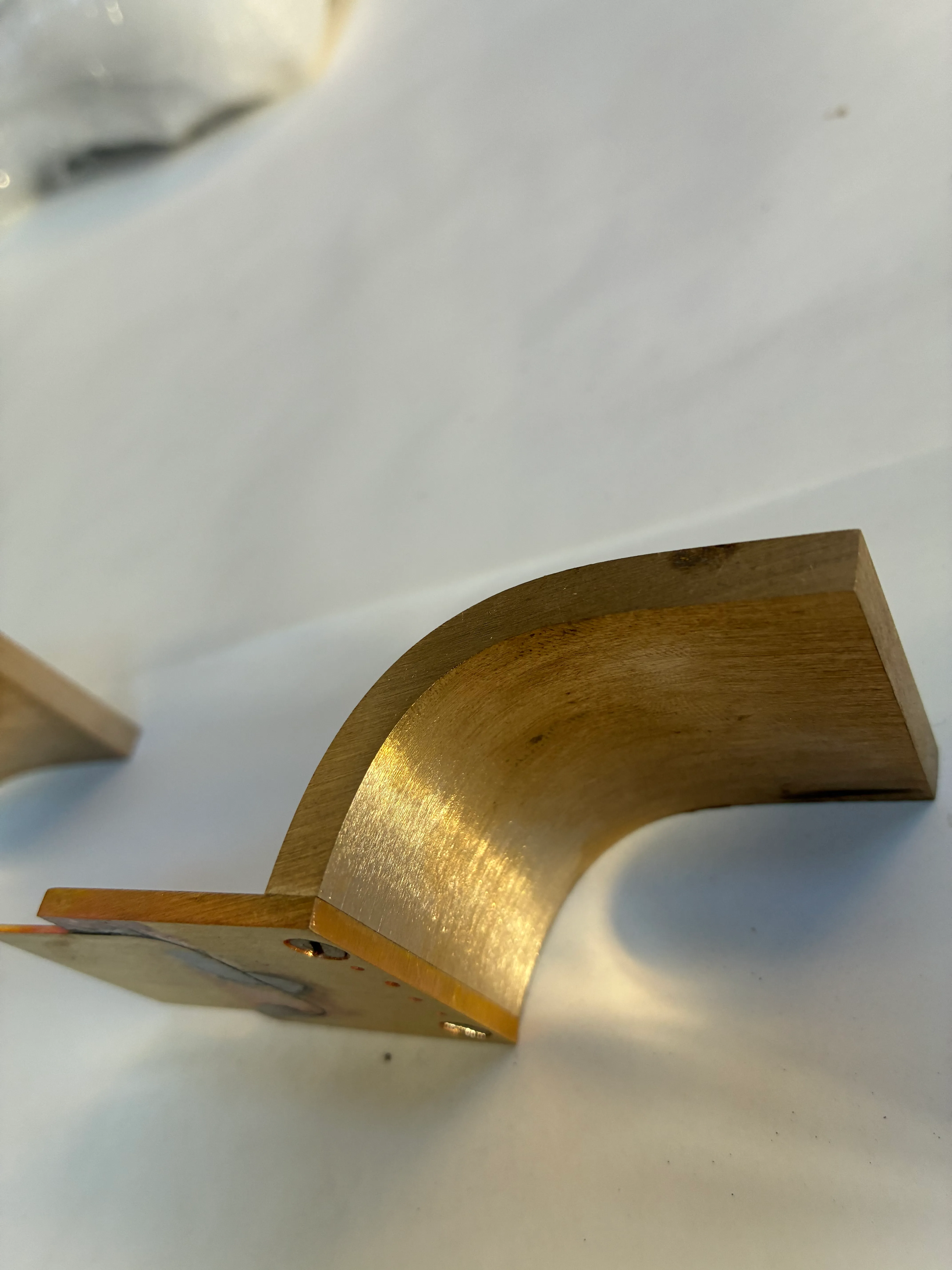 Détail technique d'assemblage d'une poignée en laiton sur mesure - L'Atout Faire Vue très rapprochée de la soudure et des vis sur la plaque de montage d'une pièce en laiton