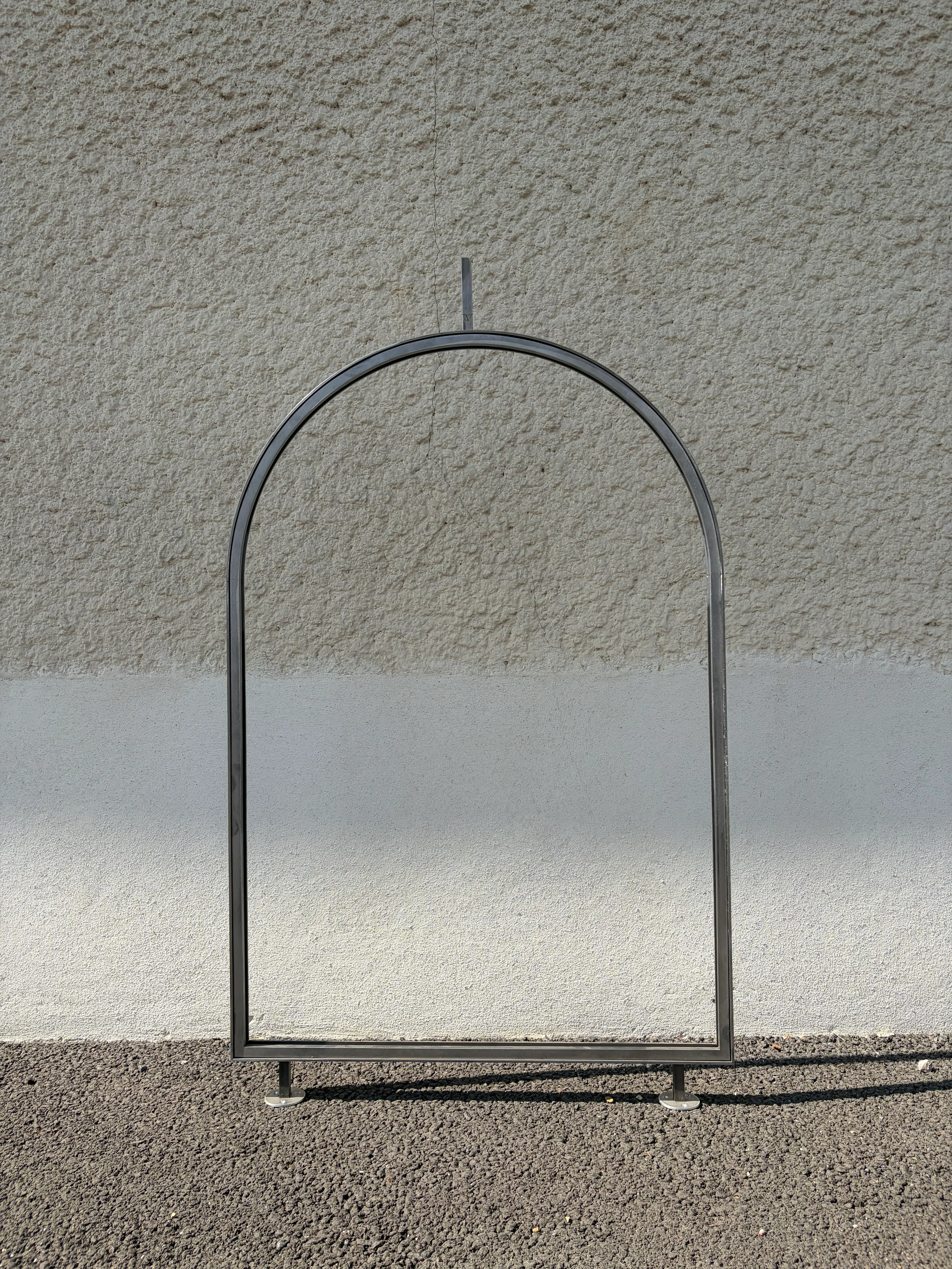 Châssis sur mesure en acier brut pour vitrail en niche intérieure Châssis en acier brut cintré vide, fabriqué sur mesure pour recevoir un vitrail en niche intérieure, posé contre un mur.